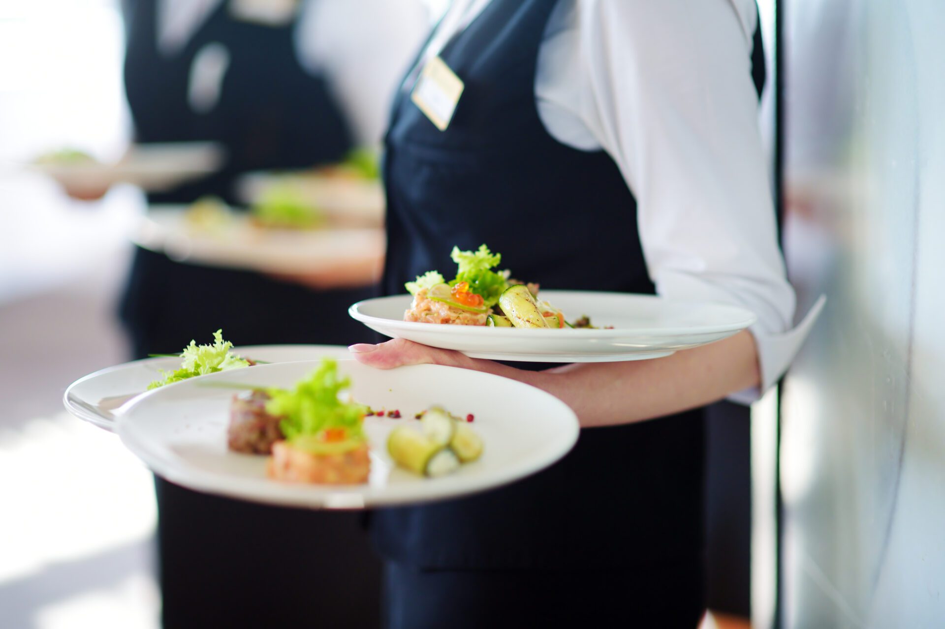 Waiter carrying plates with meat dish on some festive event, party or wedding reception